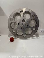 Front view of aluminum 35mm film reel next to apple for scale