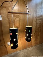 full view of two black cylinder pendants hanging from wooden bar