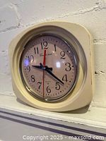 Front view of beige plastic wall clock showing dial, hands and frame
