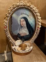 Full front view of seashell-framed Saint Rita lamp showing frame, print, shells and wiring