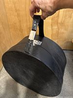Full view of round black hat box with handle