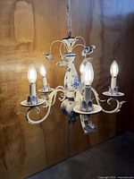 Full view of five-arm Delft-style chandelier lit with bulbs