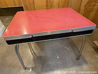 Full view of table showing red Formica top, chrome legs, pull-out leaves retracted