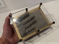 Pin art sculpture showing hand impression in metal pins