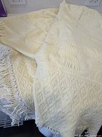 Overall view of bedcover draped to show size and fringe