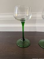 Single glass showing clear bowl, green stem and base
