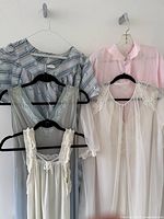 Four garments hanging: blue striped nightgown, pale blue lace V nightgown, white sheer robe, pink sheer robe