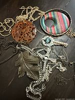 Overview of carved disc, skeleton key, maple leaf pendants, fabric donut and chains