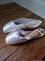 Pair of pink satin pointe shoes side view