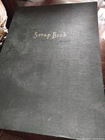 Front cover of black scrapbook titled Scrap Book
