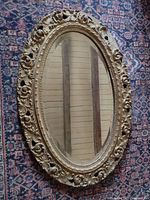 Full view of oval mirror on patterned rug background