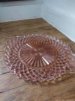Full view of round pink glass cake plate on wood floor
