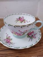 Teacup on saucer, front view showing floral pattern and gold rim