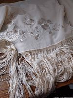 Full view of embroidered satin shawl with fringe