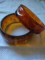 Two amber lucite bangles, carved one stacked on smooth one