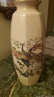 Full view of cream crackle-glazed vase showing peacock and floral design