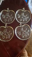 All four apple-shaped clear glass plates displayed