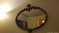 Full view of oval gilded mirror mounted on wall