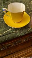 teacup on saucer showing yellow glaze, gold trim, floral handle