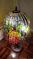 Full view of lamp illuminated showing stained glass shade and base