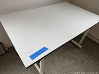 Overall view of white tilting tabletop with wear marks