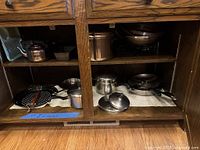 Cookware and hot plate arranged on cabinet shelves