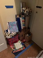 Corner with box holding multiple rolls of wrapping paper, gift bags, gift boxes, ribbons, mylar balloons