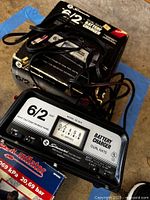 Close-up of Schumacher SE-62-6 battery charger on worn box with cords and clamps visible