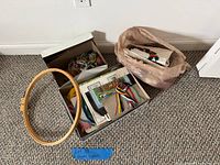 Overview of wooden hoop, boxes of floss, yarn and partial canvases