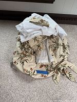 Pile showing beige floral curtains, white sheers and tiebacks