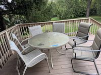 round glass patio table with five chairs on deck