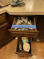 Drawer with stainless flatware, visible knives and organizer; lower drawer showing cloth napkins