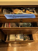 Open drawers showing utensils, containers, glass bowls, and folded linens