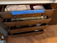 Open chest showing four drawers filled with assorted linens