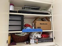 View of cabinet showing top and middle shelves with warming tray, drawer unit, Medtronic box, racks, fondue set