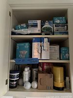 Cabinet shelves showing boxed bulbs, filters, polish containers, loose bulbs, flashlight