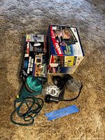 All items boxed and loose on carpet: Malibu pathway set, motion detector light box, Reflex floodlight box, green spotlight, black spotlight, glass porch light