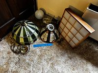 Lot overview showing two stained-glass shades, wood grid box, brass lantern, white globe, hardware