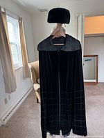 Cape hanging full view with matching hat on hanger