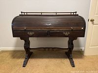 Front view of closed roll-top desk showing overall design, exterior drawers, trestle legs