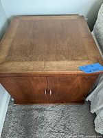 Square medium brown wood end table/nightstand with two cabinet doors and knob pulls