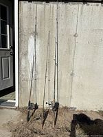 Three fishing rods leaning against wall showing full length
