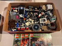 Box of loose LEGO bricks and parts with manuals visible at front