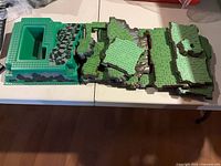Stack of assorted green terrain panels beside large raised baseplate