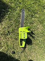 Full view of Poulan green electric chainsaw lying on grass