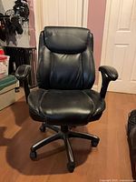 Front view of black faux-leather swivel office chair showing seat, back, armrests and base