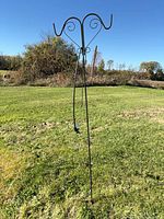 Full view of black double shepherd’s hook standing upright on lawn