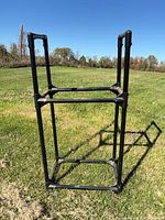 Full view of black tubular tire rack standing on grass
