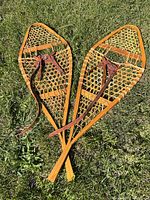 Pair of wooden snowshoes crossed on grass