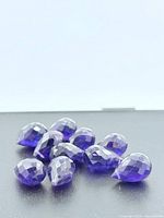 Group of 12 faceted amethyst briolette beads on black background
